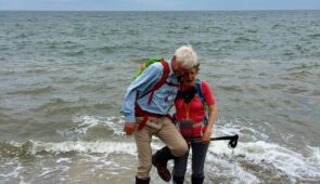 Walkers dipping their boots in the North Sea at Robin Hood's Bay