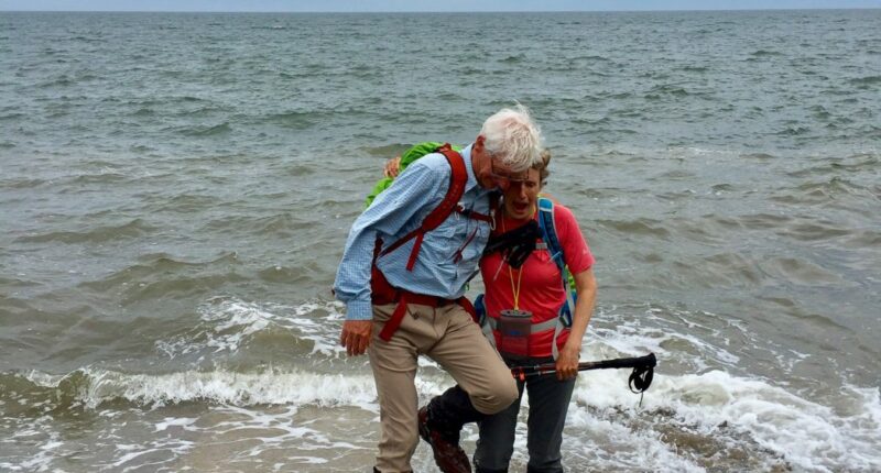 Walkers dipping their boots in the North Sea at Robin Hood's Bay