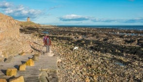 Walkers on the beach at St Monans with the St Monans Windmill seen in the background