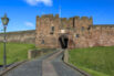 Carlisle Castle, a medieval stone fortress with high walls and towers set against a blue sky
