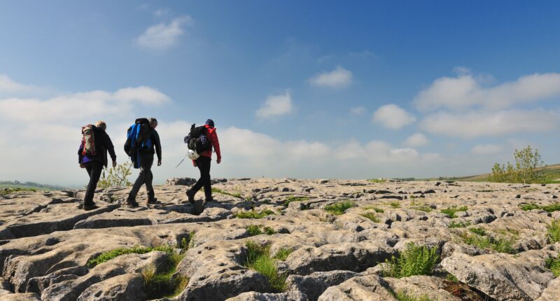 Walkers on the limestone pavement above the cliffs of Malham Cove