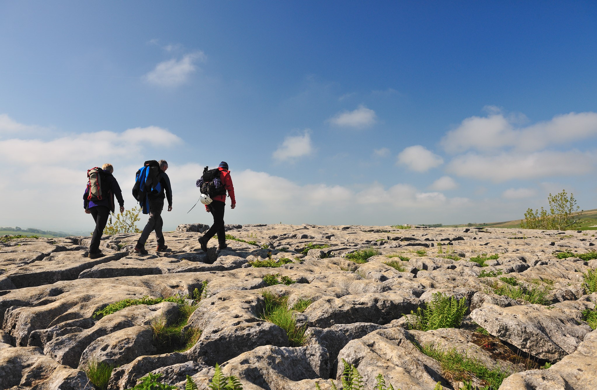 Walkers on the limestone pavement above the cliffs of Malham Cove