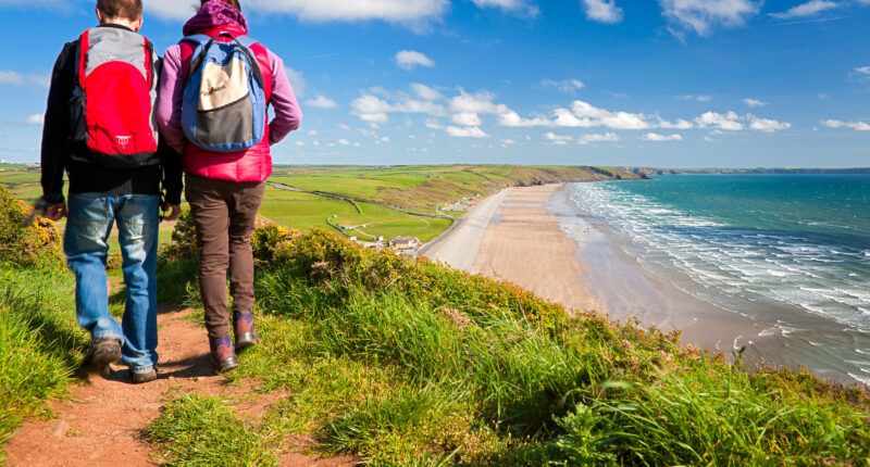 Couple walking on the trail with Newgale beach in distance