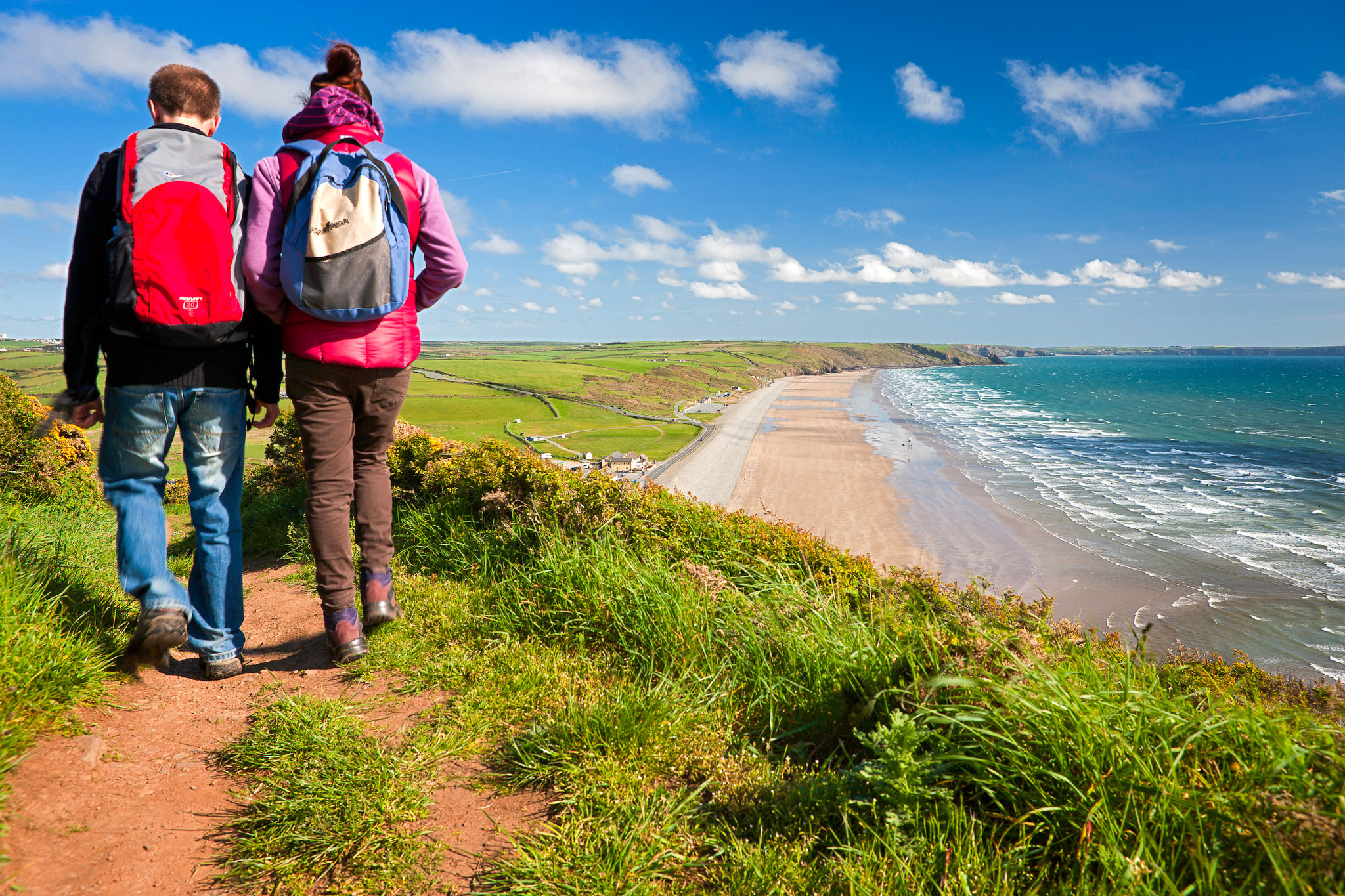 Couple walking on the trail with Newgale beach in distance