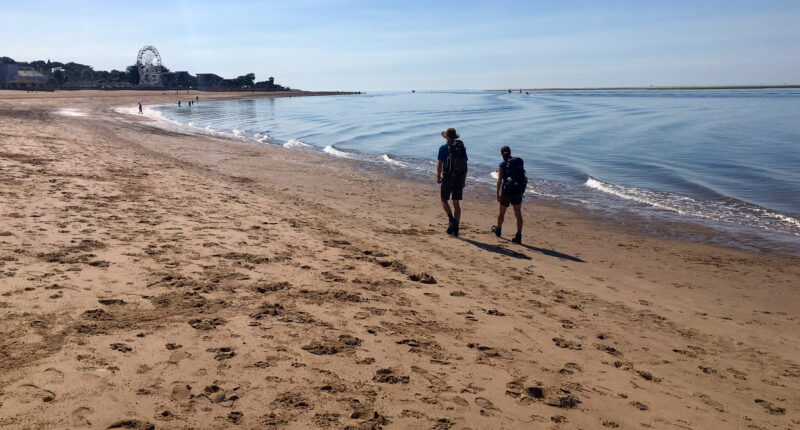 Hikers walking on the beach on the South West Coast Path