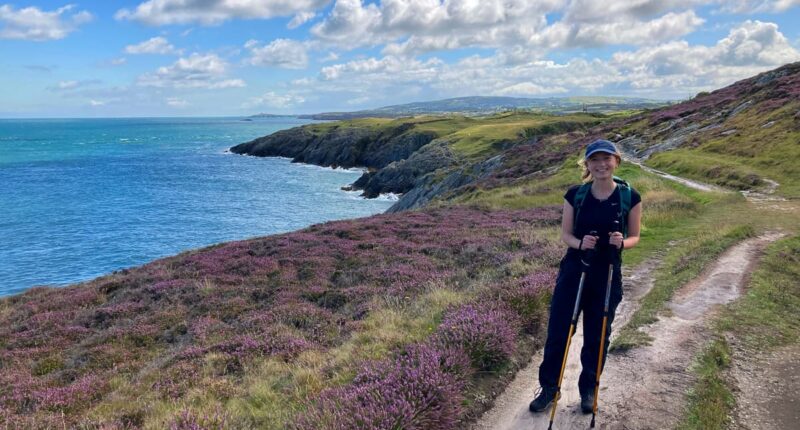 Daisy from the Absolute Escapes team walking along the coastline near Trwyn Myn