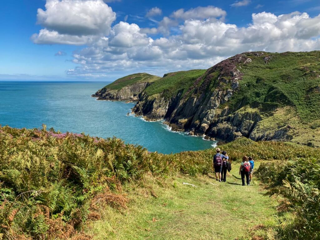Walkers approaching the dramatic cliffs near Porth Cynfor on the Isle of Anglesey Coastal Path.
