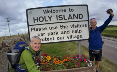 Hikers approaching Holy Island of Lindisfarne while walking St Cuthbert's Way