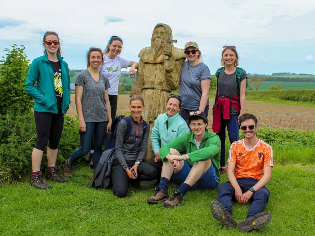 Group of walkers at St Cuthbert's statue on the pilgrim trail