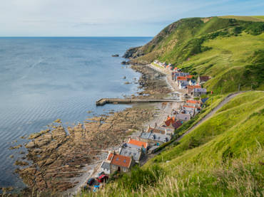 Quaint fishing village of Crovie in Aberdeenshire featured in road trip itineraries in Scotland - traditional coastal cottages nestled beneath dramatic cliffs