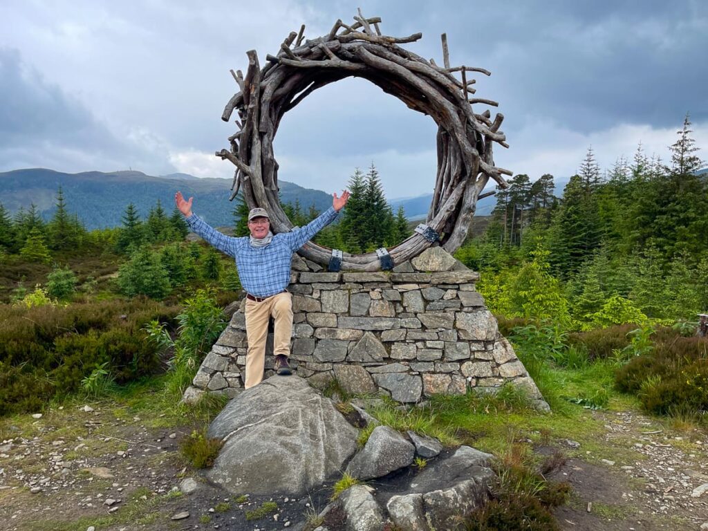 Hiker at stone arch trail marker on the Great Glen Way