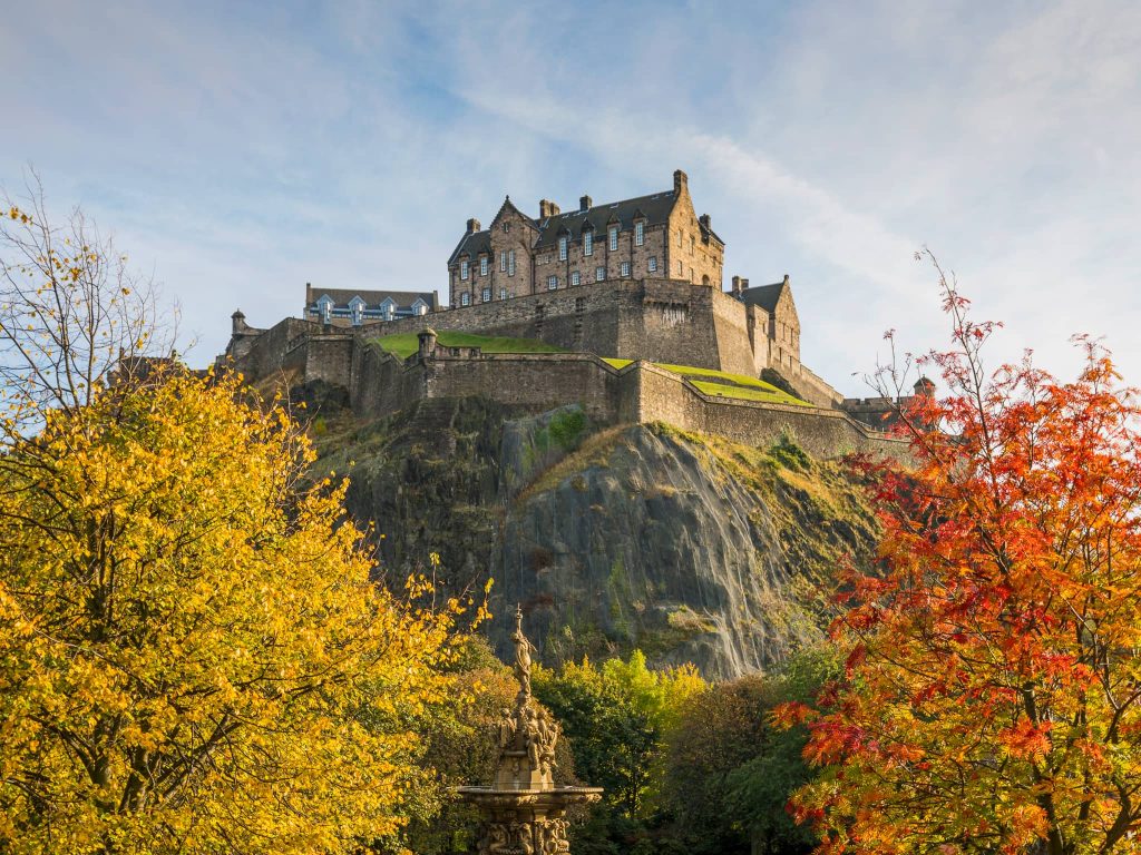Edinburgh Castle in autumn surrounded by golden foliage, ideal for travellers planning where to go in the UK in October