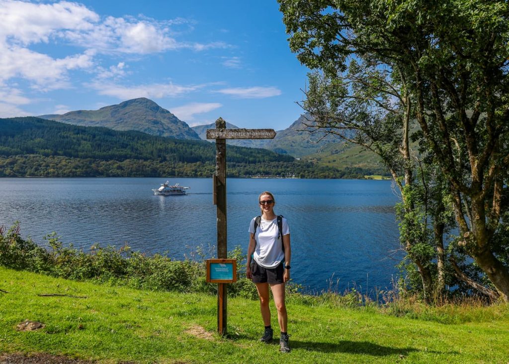Absolute Escapes travel specialist beside the West Highland Way sign at Loch Lomond in the Scottish Highlands